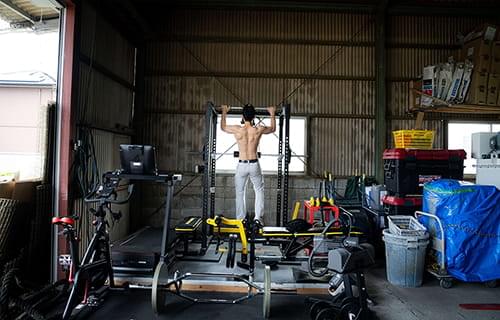 倉庫の中で懸垂をする上半身裸の男性